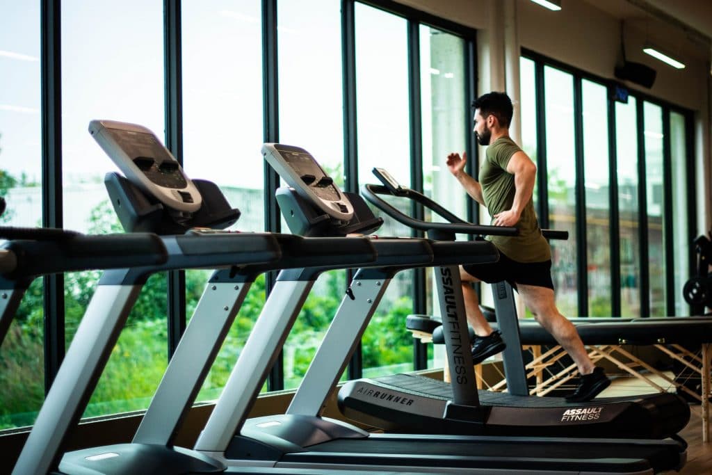 Homme qui court sur un tapis de course dans une salle de sport